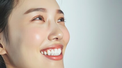 Obraz premium Close-Up of Young Asian Woman's Radiant Smile, Emphasizing Perfect White Teeth on Clean White Background
