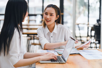 Two businesswomen reviewing and discussing data charts during meeting in modern office.