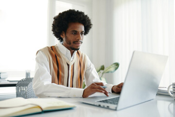 Startupper working on laptop in small office