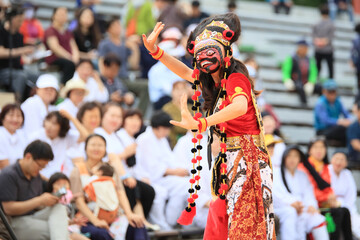 A person performing a mask dance performance in a traditional Indonesian costume