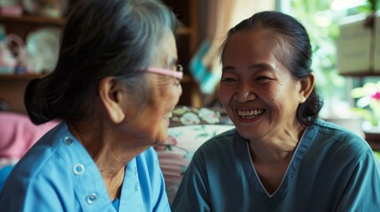 Caring Young Asian Nurse Engaging in Friendly Conversation with Happy Senior Asian Woman at Home