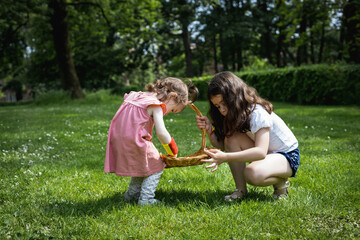 Fototapeta premium Portrait of two girls decorate a basket with daisies on a summer day.