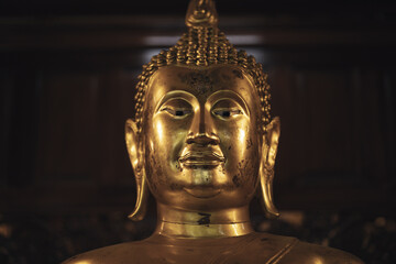 Golden Buddha head under light and shadow inside an old temple in Phra Nakhon Si Ayutthaya Province, Thailand.