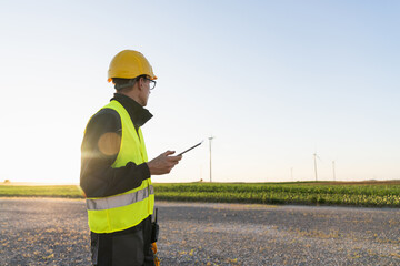 Engineer with digital tablet works on a field of wind turbines