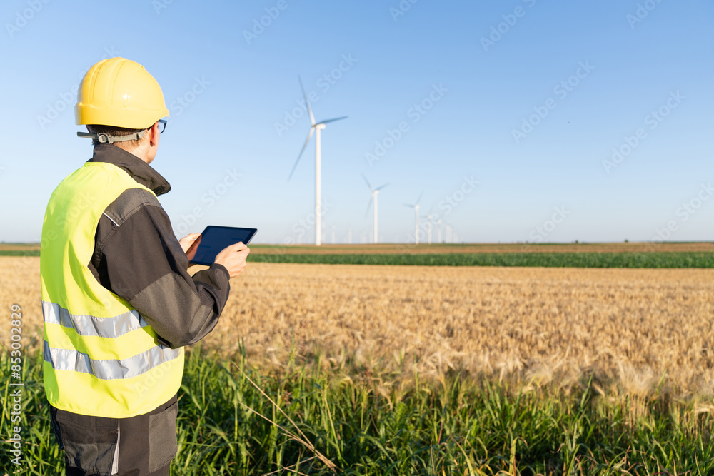 Aufkleber engineer with digital tablet works on a field of wind turbines