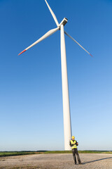 Engineer with digital tablet works on a field of wind turbines