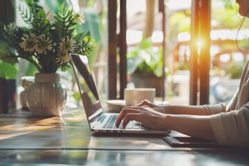 Woman freelancer typing on laptop at sunny coffee shop, searching online, close up view