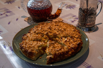 Homemade apple pie with tea and a glass in a cup holder on a rustic table