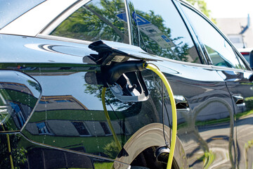 Electric car is charging, close-up of plugged-in cable