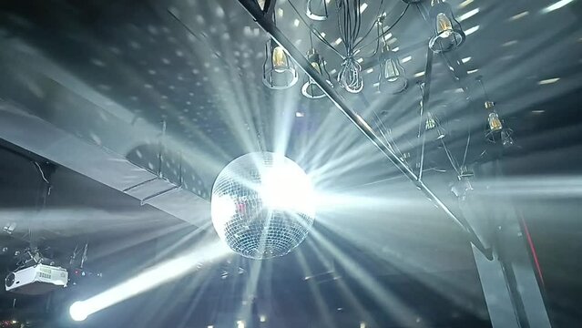 Silver mirror disco ball in the rays of the spotlights