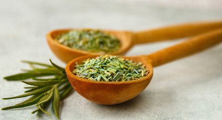 Rosemary in a wooden spoon. Dry and fresh fragrant rosemary, seasonings on a light background. Spices and herbs that are used for cooking meat and fish. Culinary concept.