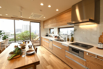 Cocina moderna de madera clara con mesa en el medio llena de objetos de preparaci&oacute;n de alimentos