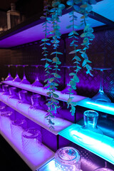 Glasses for wine, martinis, and cocktails are displayed on a purple and blue light bar.