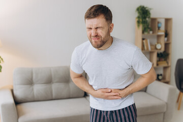 Stomach ache, man with abdominal pain suffering at home, health problems concept