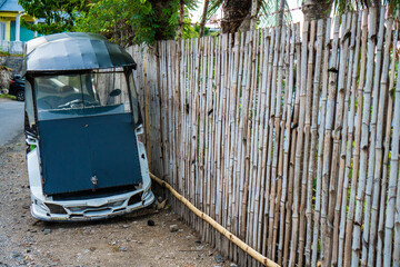 Bentor or motor rickshaws are parked in front of the bamboo fence