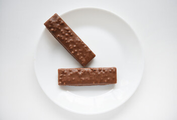 A sweet chocolate bar on a white plate.Waffle chocolate bar on a white background.