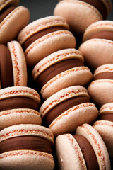 French dessert macaron filled with dark chocolate ganache. Macarons are on a dark background. Top view. 