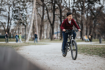 Fototapeta premium A young boy rides his bicycle along a path in an urban park, surrounded by greenery and enjoying the fresh air.