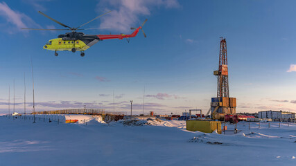 Collage. Yellow helicopter in the foreground. Drilling rig infrastructure on the Arctic oil and gas field in the background © mangz