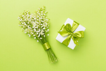 Lilies of the valley with gift box on color background, top view