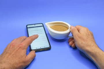 Using Smartphone with Coffee Cup on Blue Background