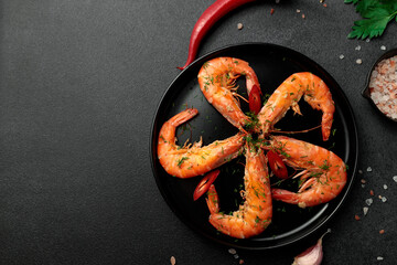 Large cooked king prawns on a black background. Lemon slices