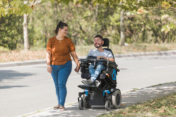 Smiling couple holding hands, a man with a disability and his wife on a pleasant autumn walk. Love,...
