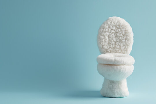 A fluffy white plushie loo on a blue background. A soft toy decor toilet.