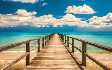 Obraz premium Woodend boardwalk leads to a beach with a blue sky and clouds in the background.