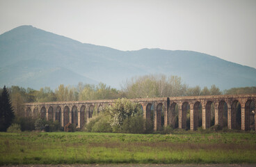 Road bridge. Roman architecture. Old stone bridge or viaduct in spring mountains. Italy.