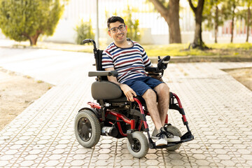 A 40-year-old disabled adult male is sitting in an automatic wheelchair.The disabled man is looking at the camera happily.Concept of a man with cerebral palsy.