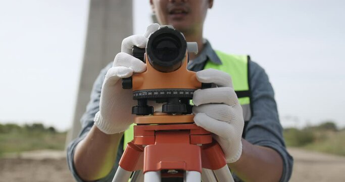 Civil engineer working with theodolite under a road construction bridge.  engineer surveyor is taking measurements with surveying instruments during a new road construction.