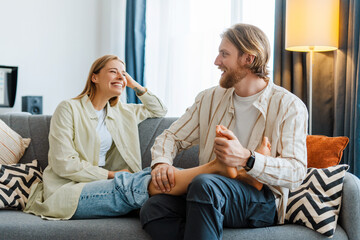 Caring man giving relaxing foot massage to woman on sofa