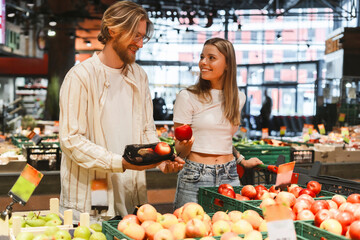 Young couple choosing apples together in grocery store