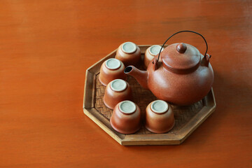 Set of baked clay kettle and cups on octagon tray.