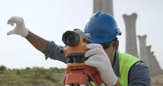 Civil engineer working with theodolite under a road construction bridge.  engineer surveyor is taking measurements with surveying instruments during a new road construction.
