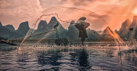 Wanddecoratie Guilin silhouette of an old cormorant fisherman on the Li river in China, Guilin   © Agata Kadar