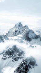 Obraz premium Snow-capped mountain peak surrounded by mist and clouds. Sharp ridges and rugged terrain create a dramatic landscape under a soft blue sky, highlighting the majesty of nature.