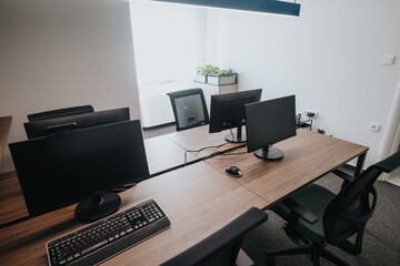 A professional office setup featuring a long wooden desk with several monitors and ergonomic chairs, ideal for team collaboration and individual efficiency.