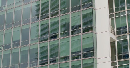 Obraz premium Exterior of contemporary high-rise office building. Floor-to-ceiling glass windows. Concept of modern architecture, corporate environment, and urban skyline. Urban background.