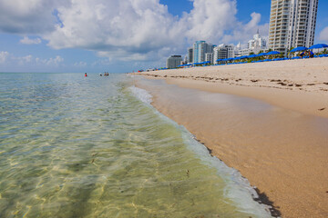Skyscrapers stretch along the Miami Beach coastline, merging with equipped sandy beaches featuring...