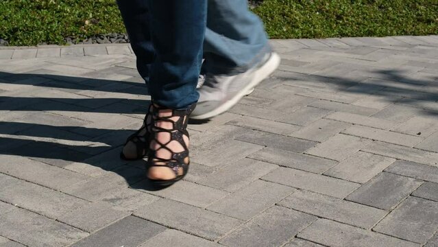 Legs of dancing people, black high-heeled dancing shoes and sneakers in jeans, couple dancing. bachata in nature