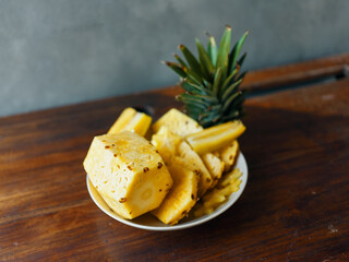 Freshly sliced pineapples and whole fruit displayed on rustic wooden table in tropical setting