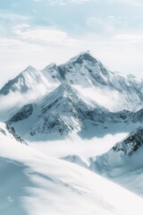 Obraz premium Snow-covered mountain range under a clear sky, with peaks shrouded in mist and clouds. Pristine, tranquil winter landscape with crisp, cool atmosphere.