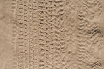 Background, texture of the uneven surface of traces, imprints from wheels, car tires, vehicles on a sandy road. Close-up photo, top view, pattern design concept.