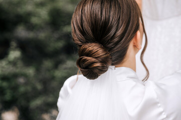 Wedding photo of a bride with brown hair, a stylish hairstyle and a bun at the back. Fashion,...