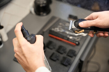 Cropped view of hairdresser cleaning hair clipper