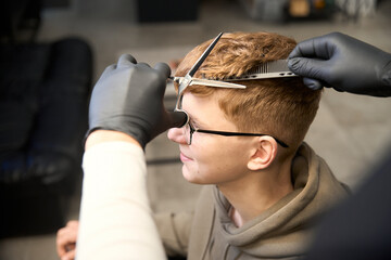 Experienced barber serving visitor in contemporary hairdressing salon