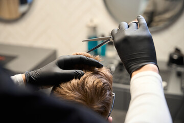 Cropped view of concentrated hairstylist working in hairdressing salon