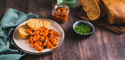 Baked beans with vegetables and rye bread on a plate on the table web banner